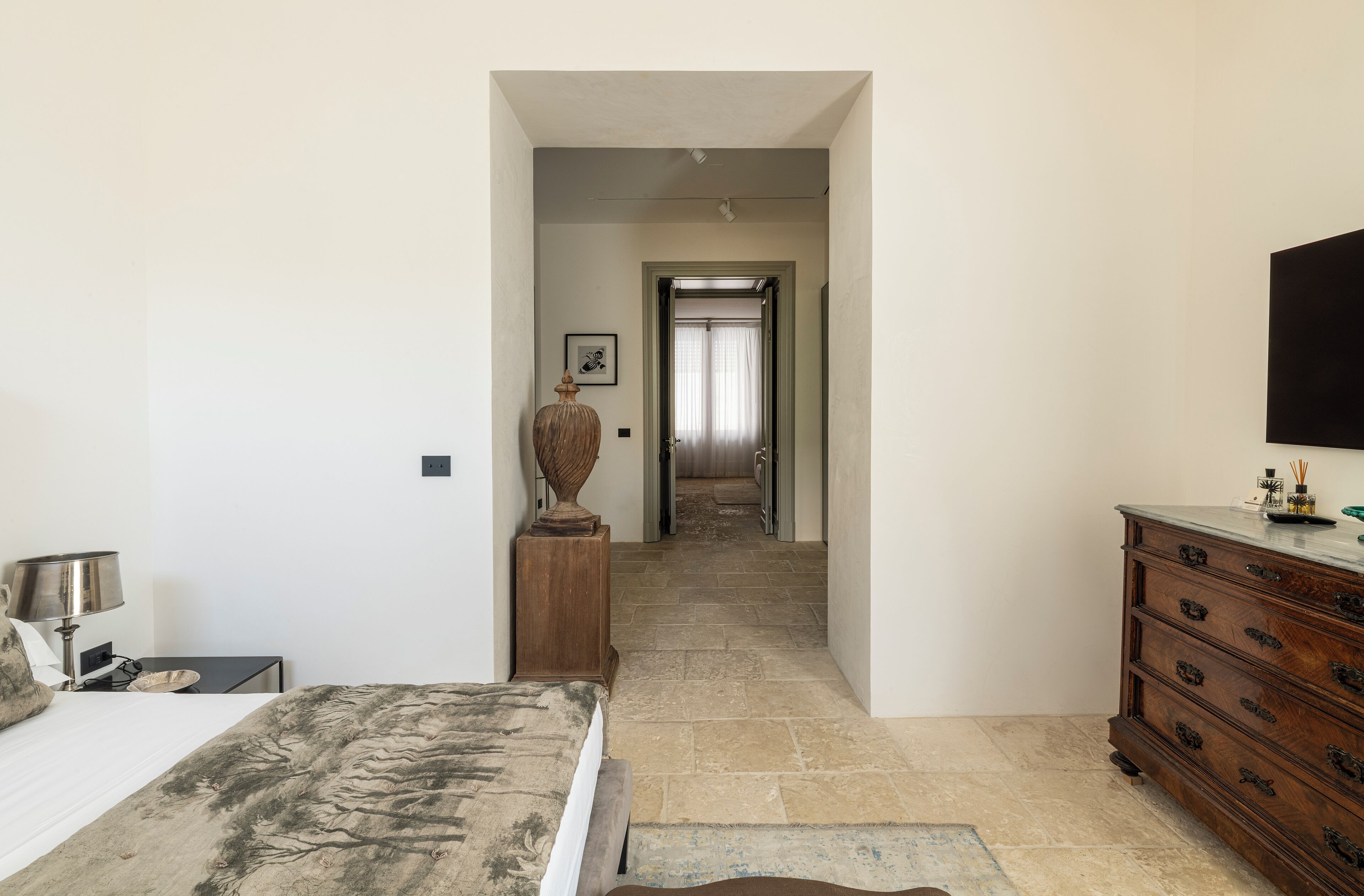 Un dormitorio con cama, cómoda y un pasillo que lleva a una puerta.