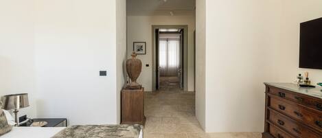 Un dormitorio con cama, cómoda y un pasillo que lleva a una puerta.