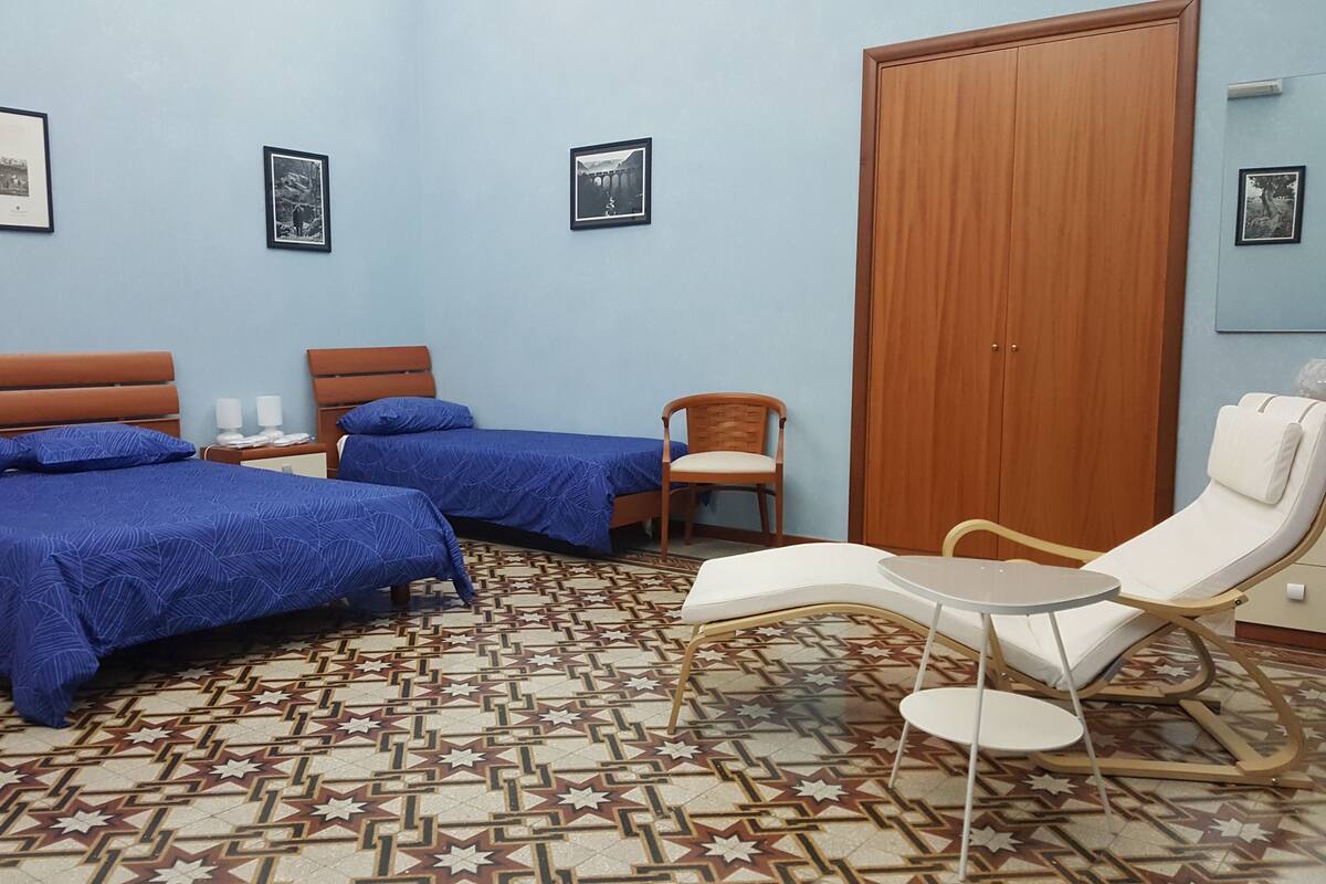 Une chambre d’hôtel avec deux lits, une chaise, une table et une armoire.
