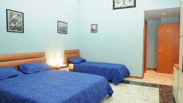 A room with two beds, a nightstand, a wall-mounted air conditioner, and a door leading to another room.