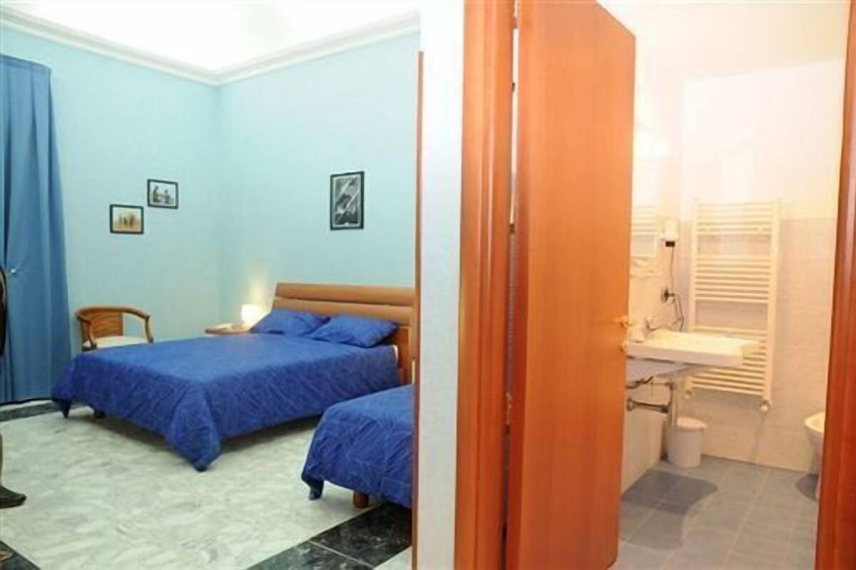 Une chambre avec deux lits, une chaise en bois et une table de chevet.