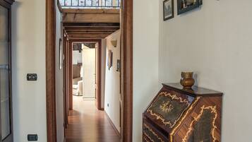 Un pasillo con un aparador de madera, piso de baldosas y una puerta que da a otra habitación.