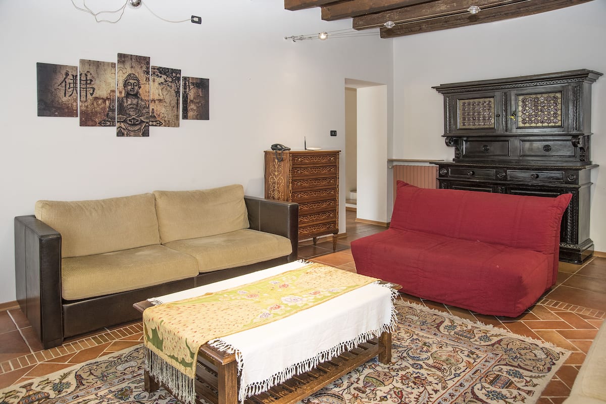 A living room with a beige sofa, a red sofa, a wooden cabinet, and a patterned rug.