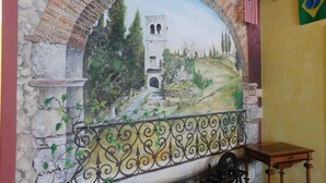 A mural of a historical building with an arched entrance, a balcony with ornate metalwork, and a flag on the wall. - Residence Villa Vinco (Tregnago)
