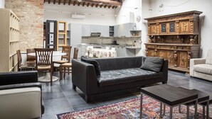 A spacious living area with a black leather sofa, a dining table with chairs, a patterned rug, and a traditional wooden cabinet. - Residence Villa Vinco (Tregnago)