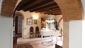 A room with a tiled floor, a chandelier, a white table, and a patterned rug. - Residence Villa Vinco (Tregnago)