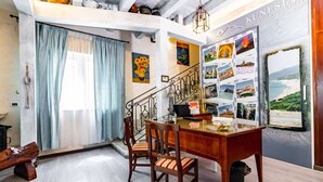 A dining area with a wooden table and chairs, a staircase, and a wall decorated with various photographs. - Kunesias (Cinisi)