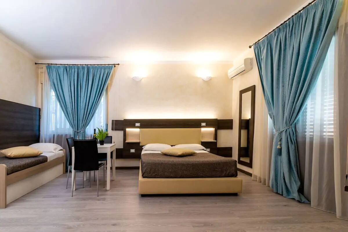 A modern hotel room with a bed, a desk, and a seating area.