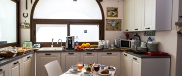 A kitchen with a dining table set for breakfast, a coffee maker, and various breakfast items.