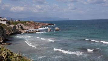 A coastal landscape with rocky cliffs and a clear view of the sea.