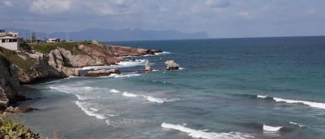 A coastal landscape with rocky cliffs and a clear view of the sea.