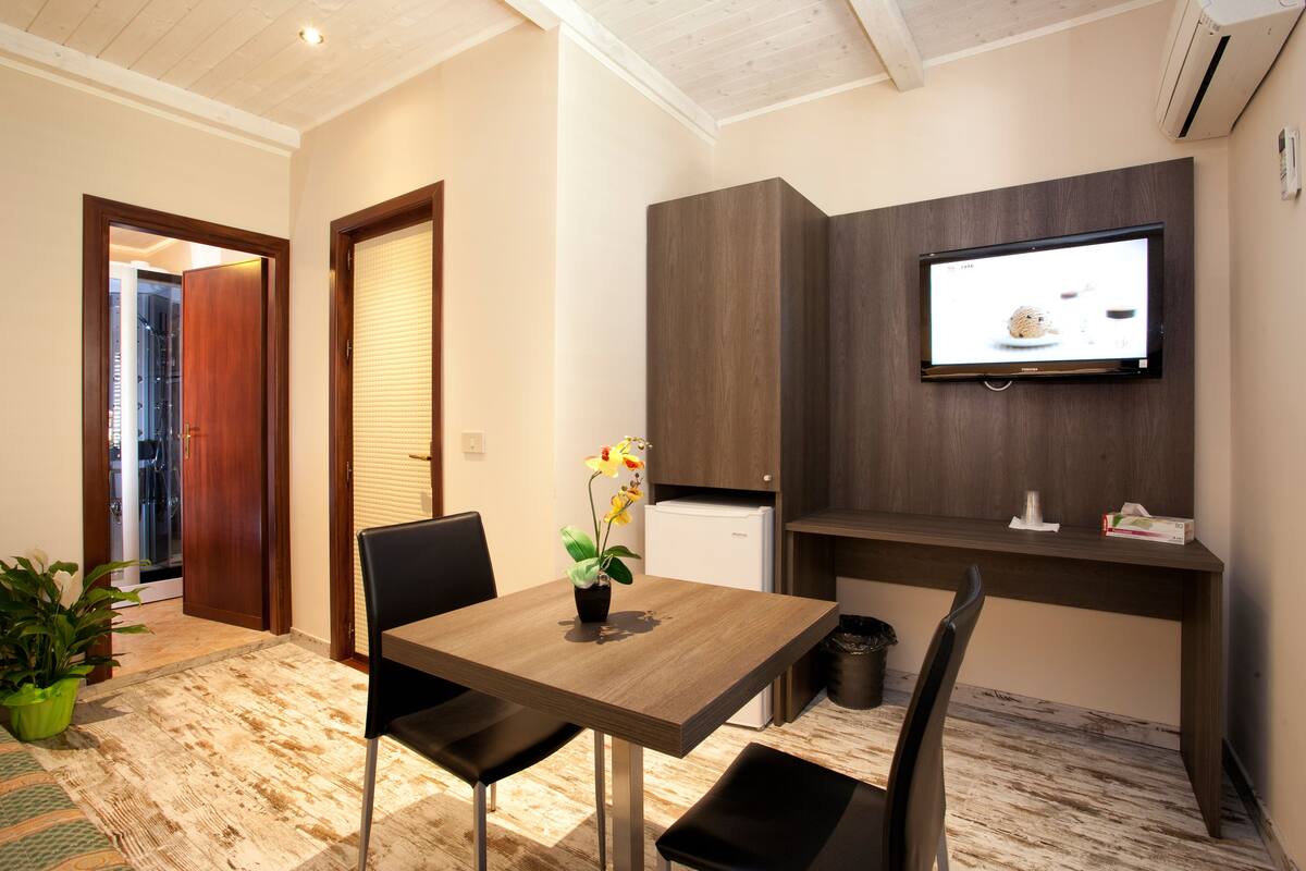 A modern kitchen with a built-in TV, a dining table with chairs, and a potted plant.