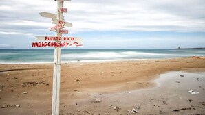 A wooden signpost with directional arrows pointing to various locations such as Puerto Rico and Magagliasur. - Kunesias (Cinisi)