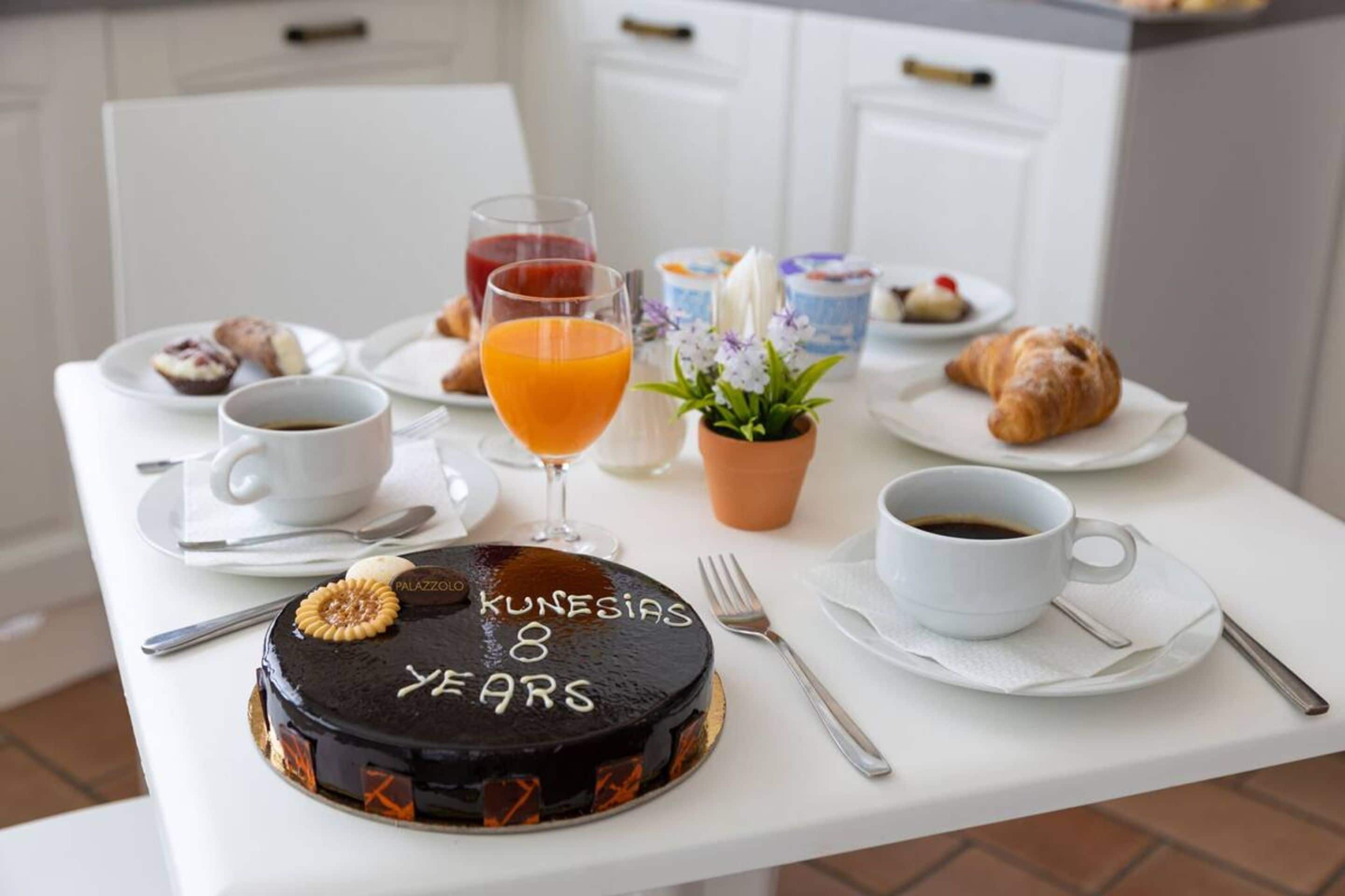 Ein Esstisch mit Schokoladenkuchen, Kaffeetassen, Saft, Croissants und Gebäck.