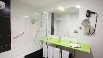 Un baño moderno con lavabo de vidrio, cabezal de ducha de mano, secador de pelo y toallero.