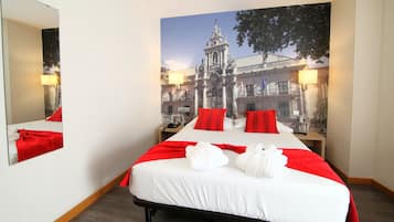 Habitación de hotel con una cama grande, almohadas rojas y un mural de un edificio.