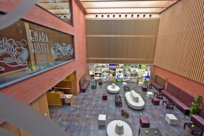 Et hotel lobby med et centralt siddeområde, en receptionsdisk og et stort vindue med hotellets navn.
