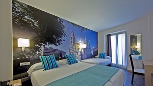 Ett hotellrum med två sängar, ett skrivbord och en stol. På väggen finns en stor väggmålning som föreställer en byggnad.
