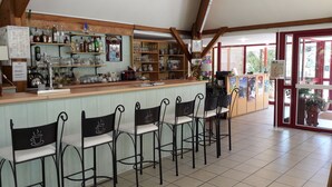 Zona de bar con mostrador, estantes con botellas y taburetes.