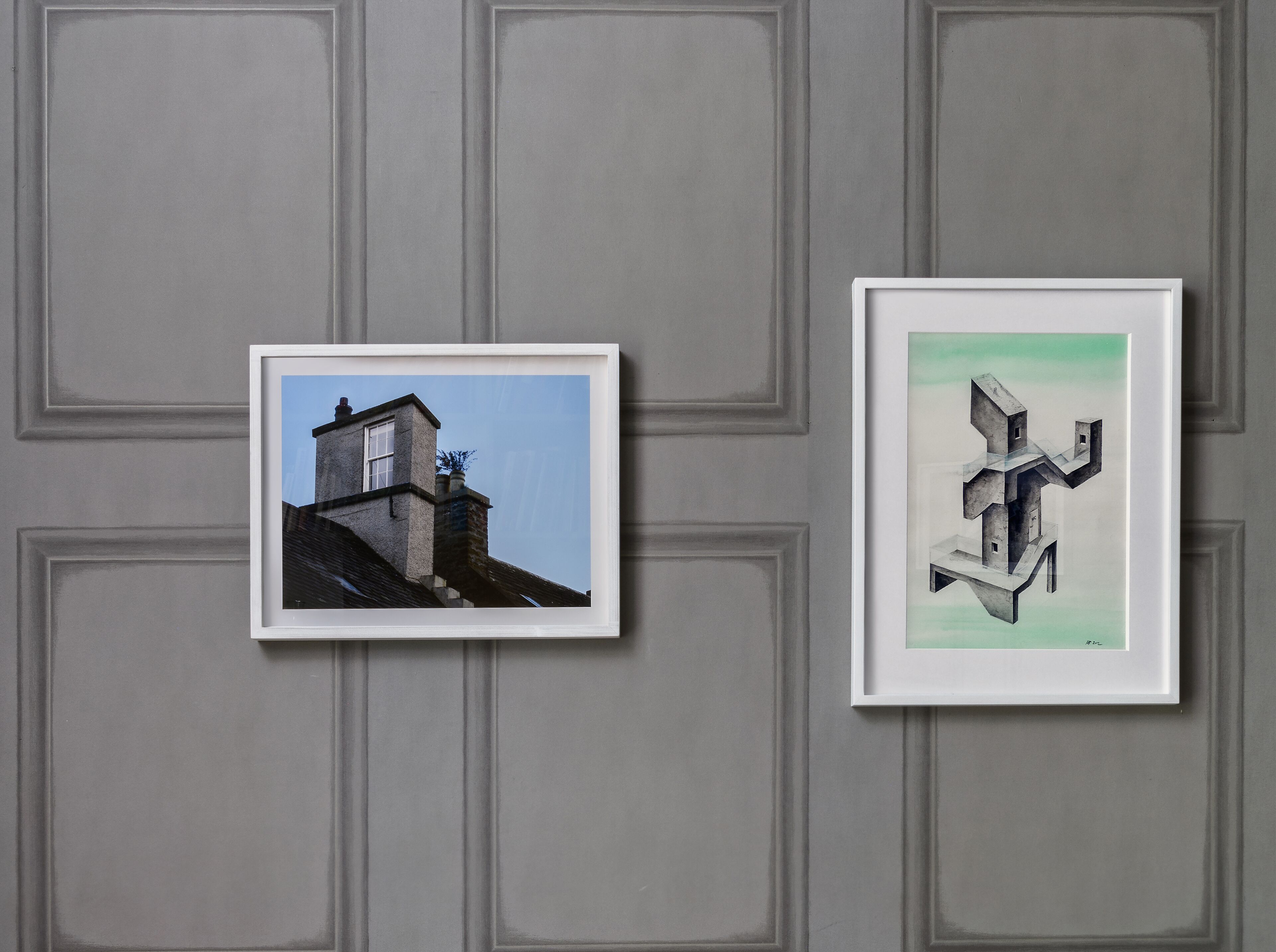 Two framed pictures on a wall with a geometric pattern.