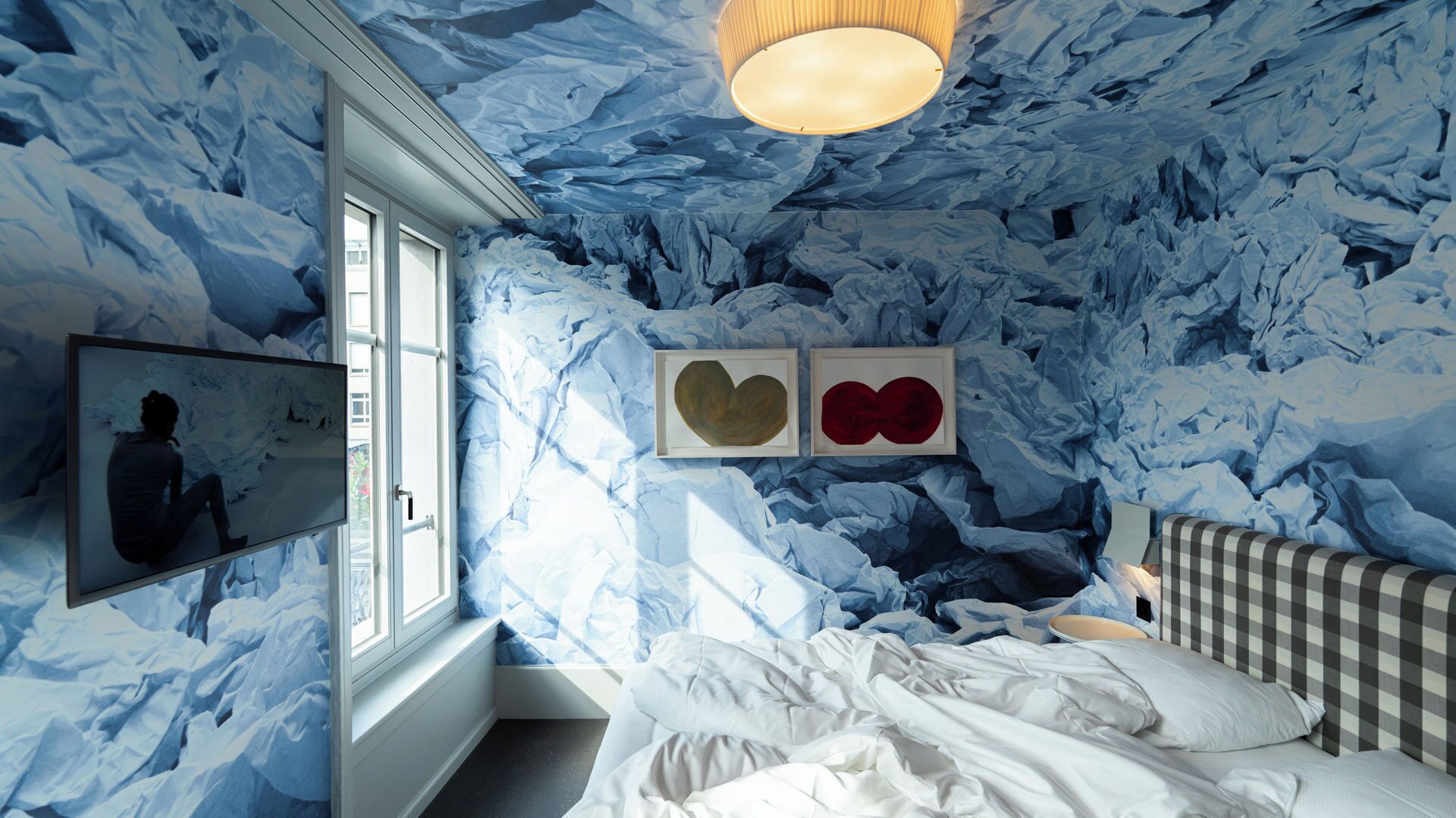A room with a bed, a window, and wall art.