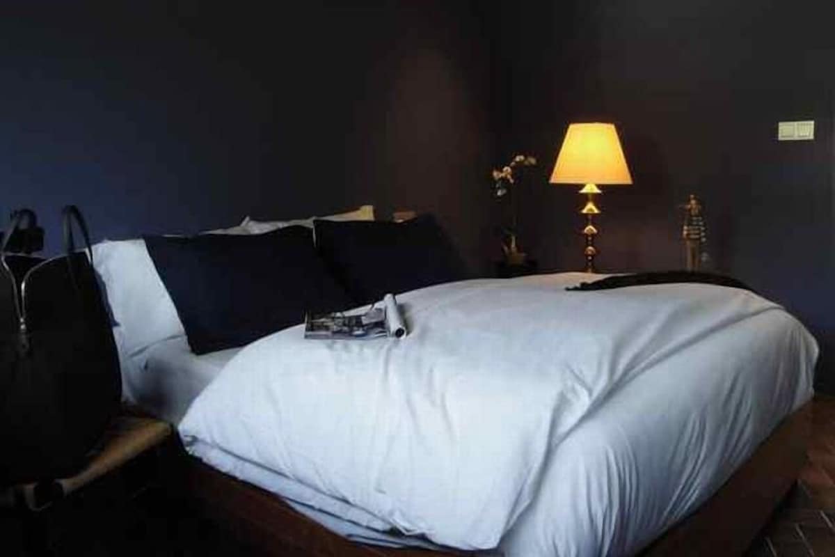 Una habitación de hotel con una cama, una mesita de noche, una lámpara y una estatua.