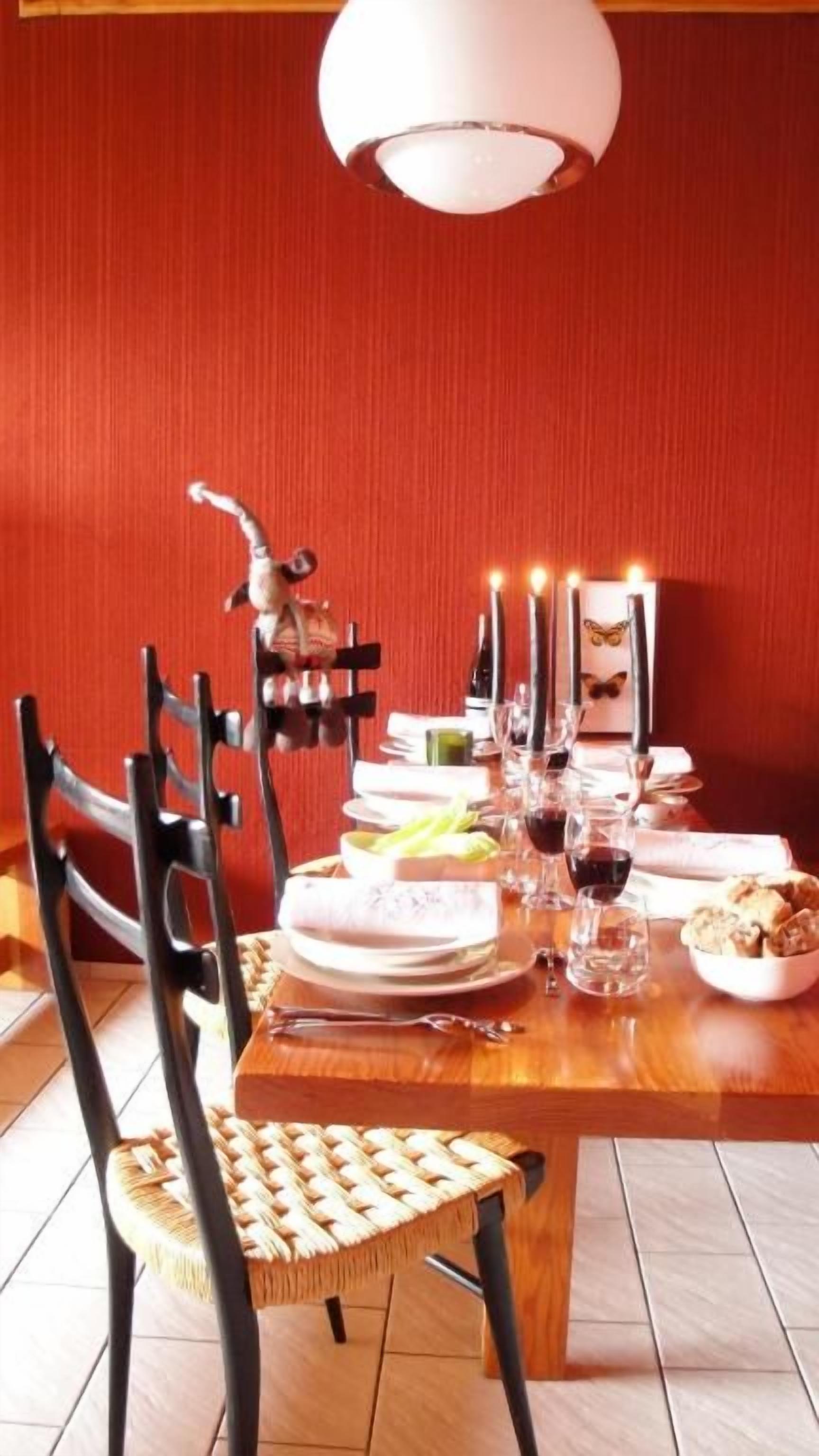 A dining table set with plates, glasses, and candles, surrounded by chairs.