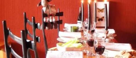 A dining table set with plates, glasses, and candles, surrounded by chairs.