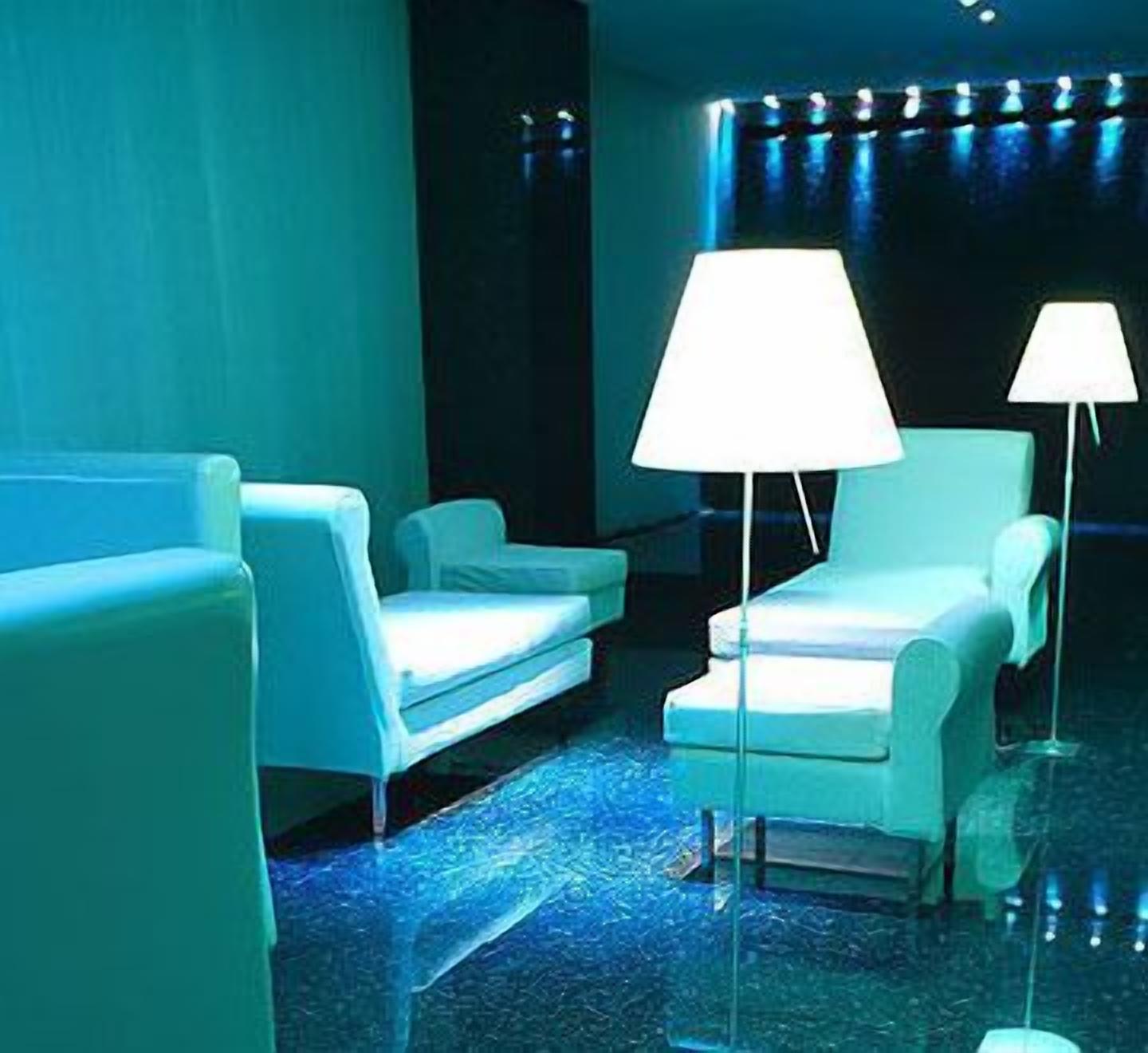 A room with white chairs and a large floor lamp.