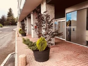 A building with a paved walkway, potted plants, and a glass entrance. - The Catalogne (Font-Romeu-Odeillo-Via)