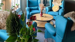 Una sala de estar con dos sillones azules, una mesa de centro y un cuadro de una persona en un muelle.