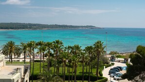 A beach view with palm trees, a parking area, and a clear sky.