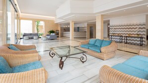 A spacious lobby with wicker furniture, a glass-top coffee table, and a modern interior design.