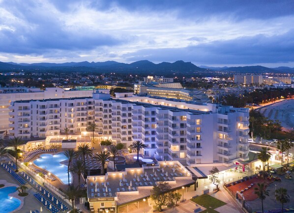 A hotel with multiple floors, a swimming pool, and a beach area.