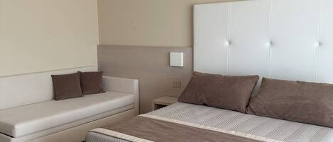 A bedroom with a large bed, a sofa, and a nightstand.