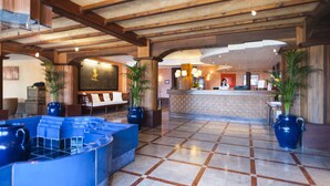 A lobby with a reception desk, seating area, and large potted plants.
