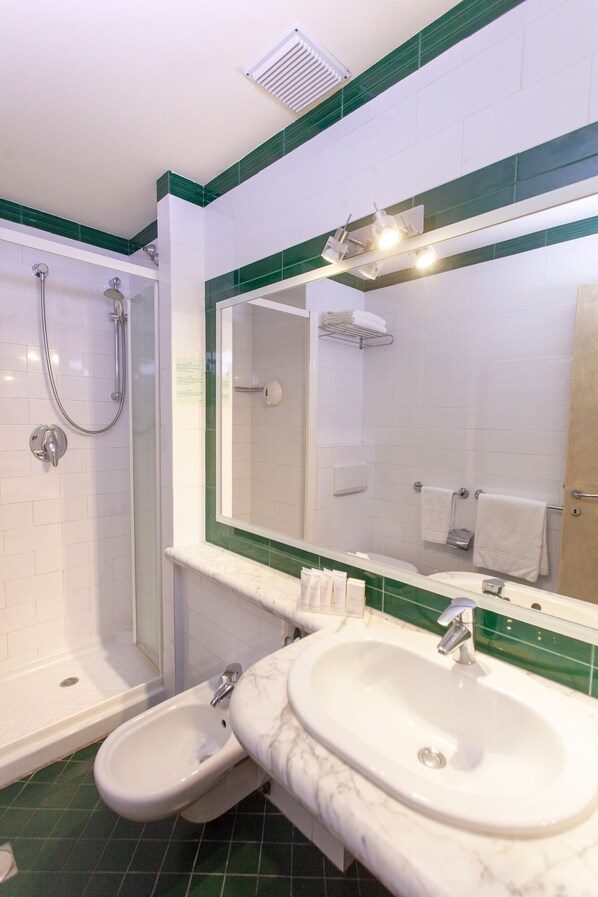 A bathroom with a shower, two sinks, and a large mirror. - Hotel La Perla del Golfo (Marciana)