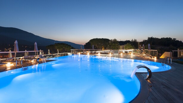 A swimming pool with a wooden deck, lounge chairs, and umbrellas.