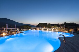 Una piscina al aire libre, sombrillas, sillones reclinables de piscina