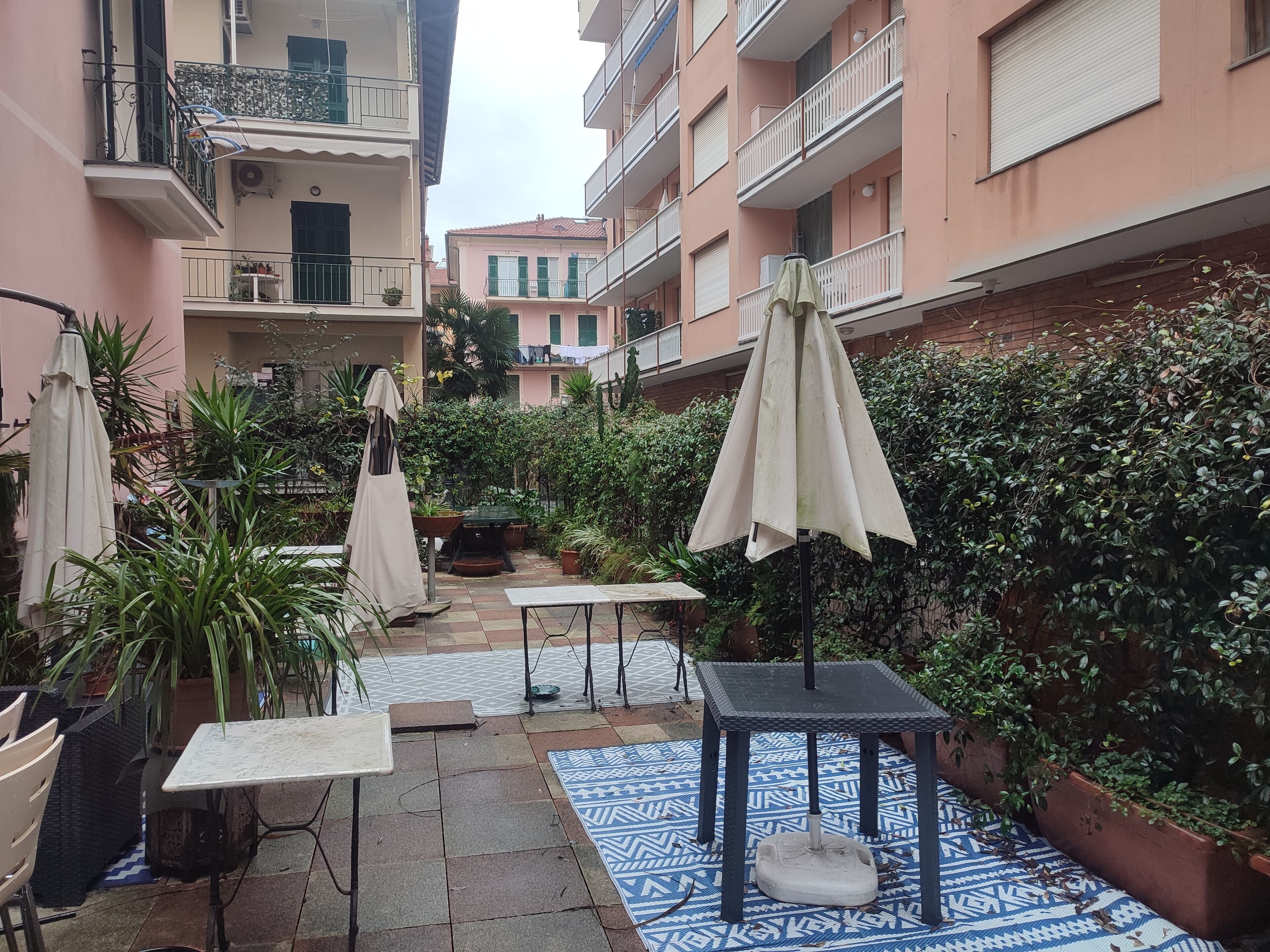 A courtyard with outdoor seating, potted plants, and a tiled floor.