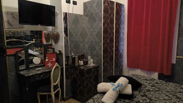 A hotel room with a bed, a desk with a computer, a chair, and a television.