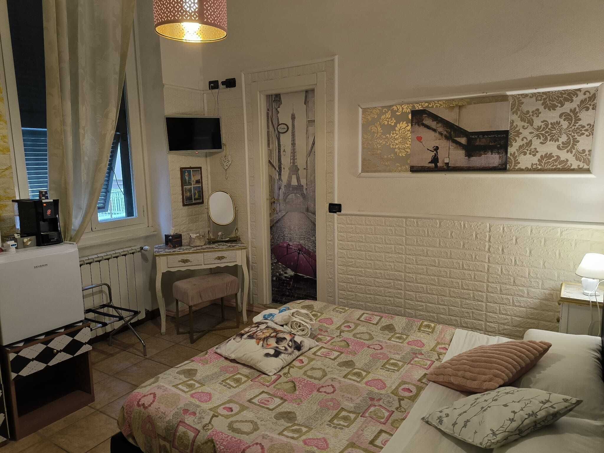 A bedroom with a bed, a dresser, a desk, and a television.