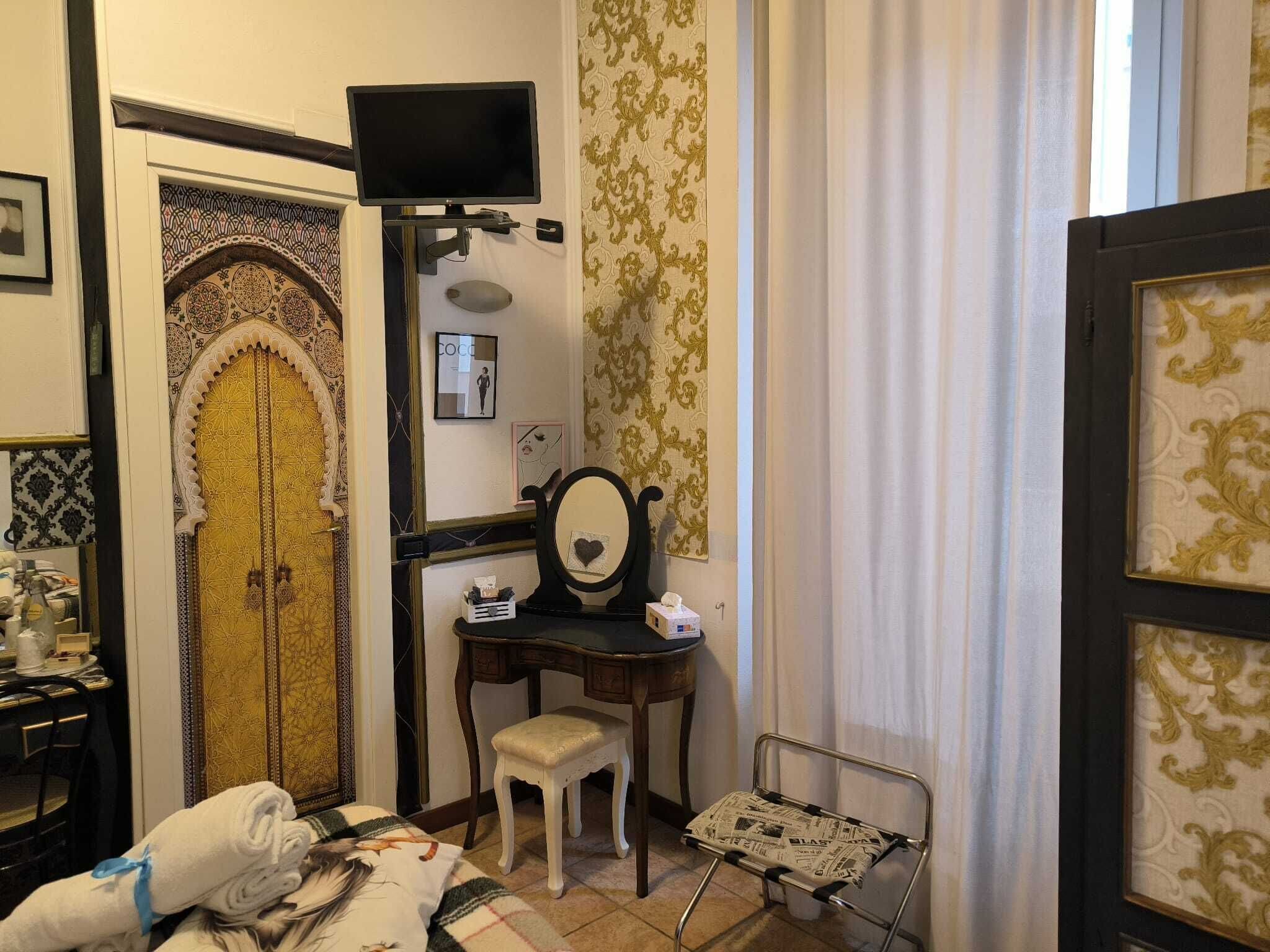Une pièce comprenant un lit, un bureau, une chaise, une télévision et un miroir.