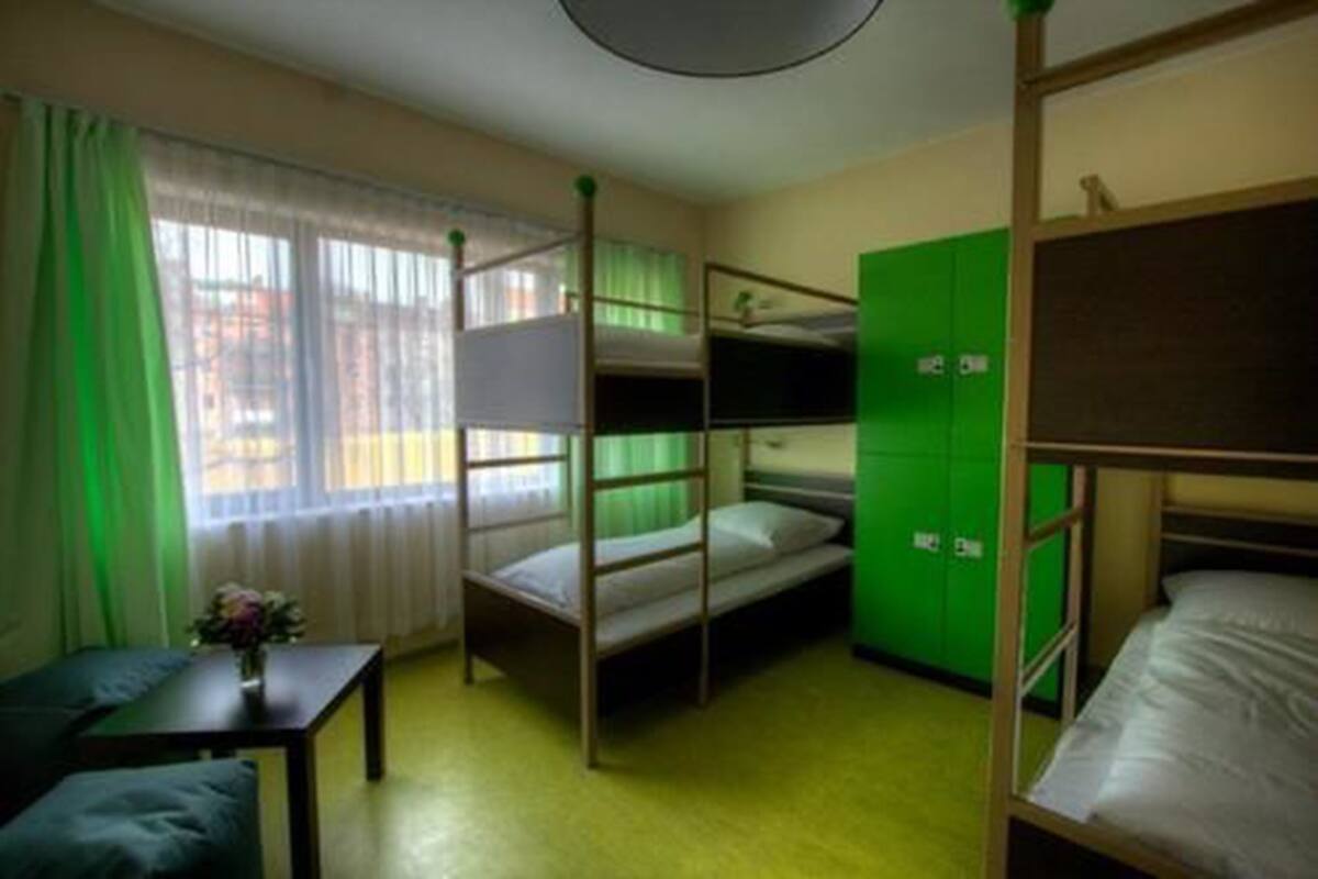 Une chambre avec un lit superposé, une fenêtre, un bureau et des casiers verts.