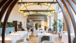A spacious dining area with multiple tables and chairs, a staircase, and potted plants. - Borgo Dei Conti Resort Relais & Chateaux (Perugia)