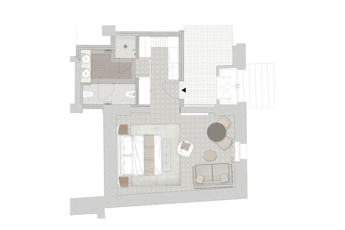 A floor plan of a hotel room with a bed, a seating area with a round table, a small kitchen, and a bathroom.