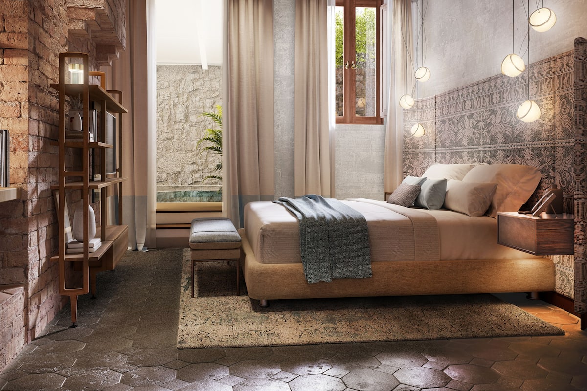 A bedroom with a bed, bedside tables, a bookshelf, and a view of the outdoors.