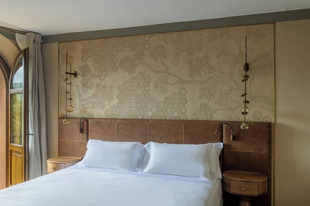 A neatly made bed with white linens, a brown headboard, and two bedside tables with lamps.