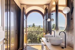 A bathroom with two large white sinks, a mirror, and a view of a balcony with a railing. - Borgo Dei Conti Resort Relais & Chateaux (Perugia)