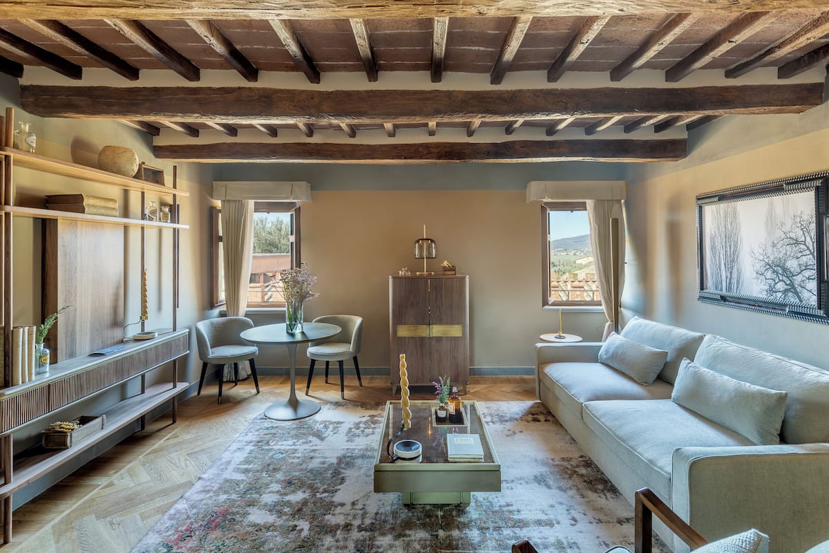 A cozy living room with a wooden ceiling, a sofa, a coffee table, and a dining area with chairs and a table.